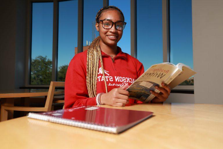 JSU student smiling while holding book